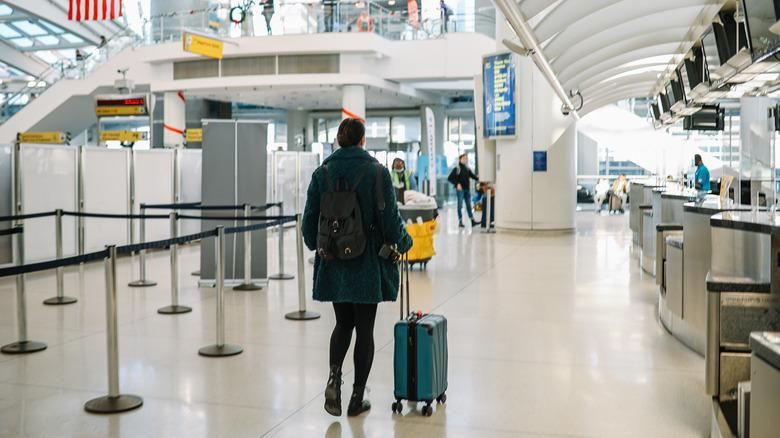 Traveler with luggage walking through an airport departures terminal