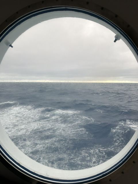 Choppier grey sea seen through a cruise ship porthole