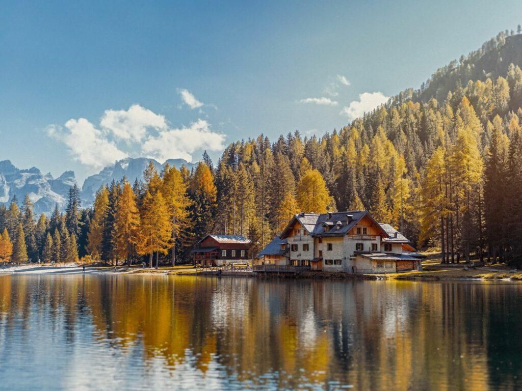 Alpine lake and church surrounded by autumn forest in Europe