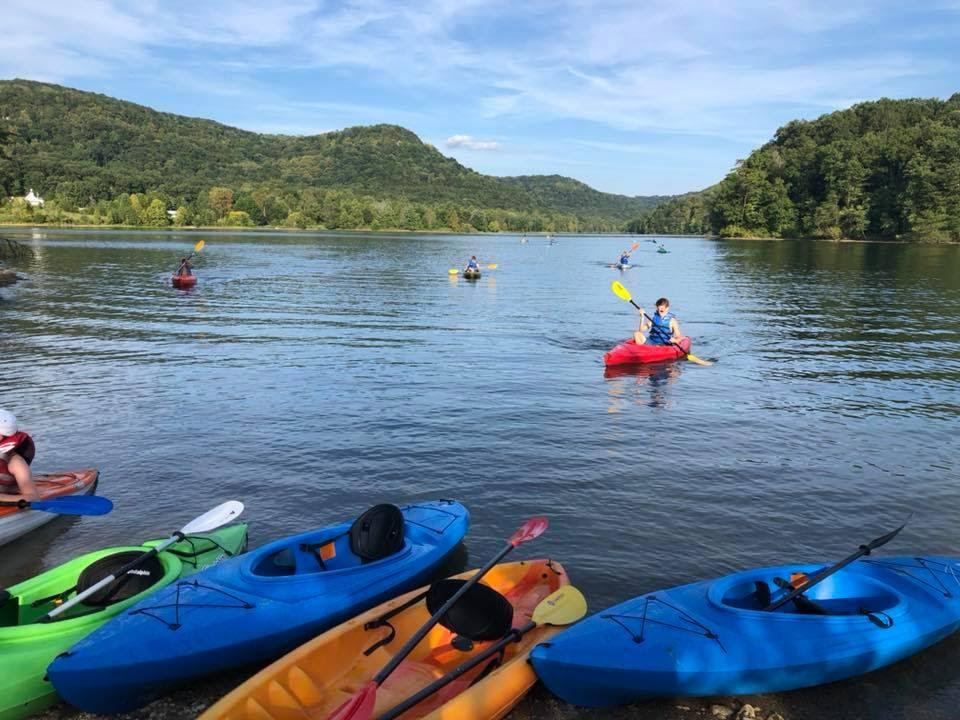 Colorful rental kayaks lined up along a Kentucky lake shore with paddlers on the water