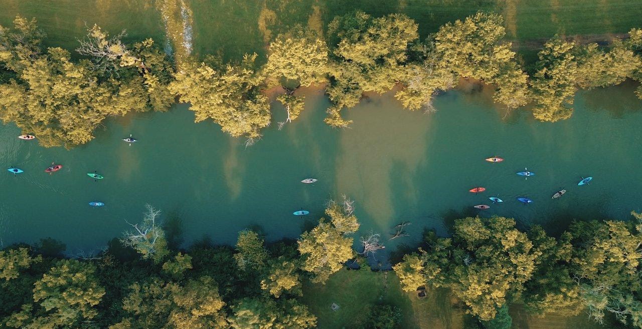 Aerial view of kayakers paddling a calm, tree-lined Kentucky river