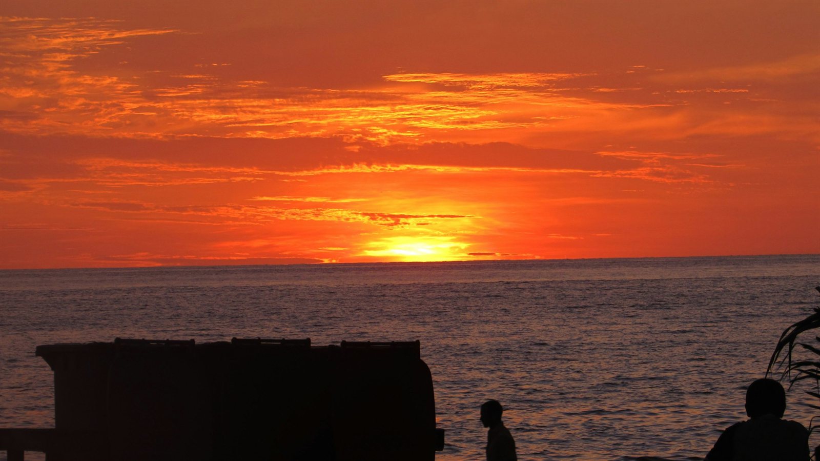 Sunset over the water on a Mexican beach with people walking along the shoreline