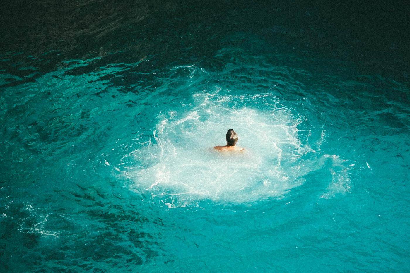 A swimmer in clear turquoise water below the cliffs at Rick's Cafe, Negril, Jamaica
