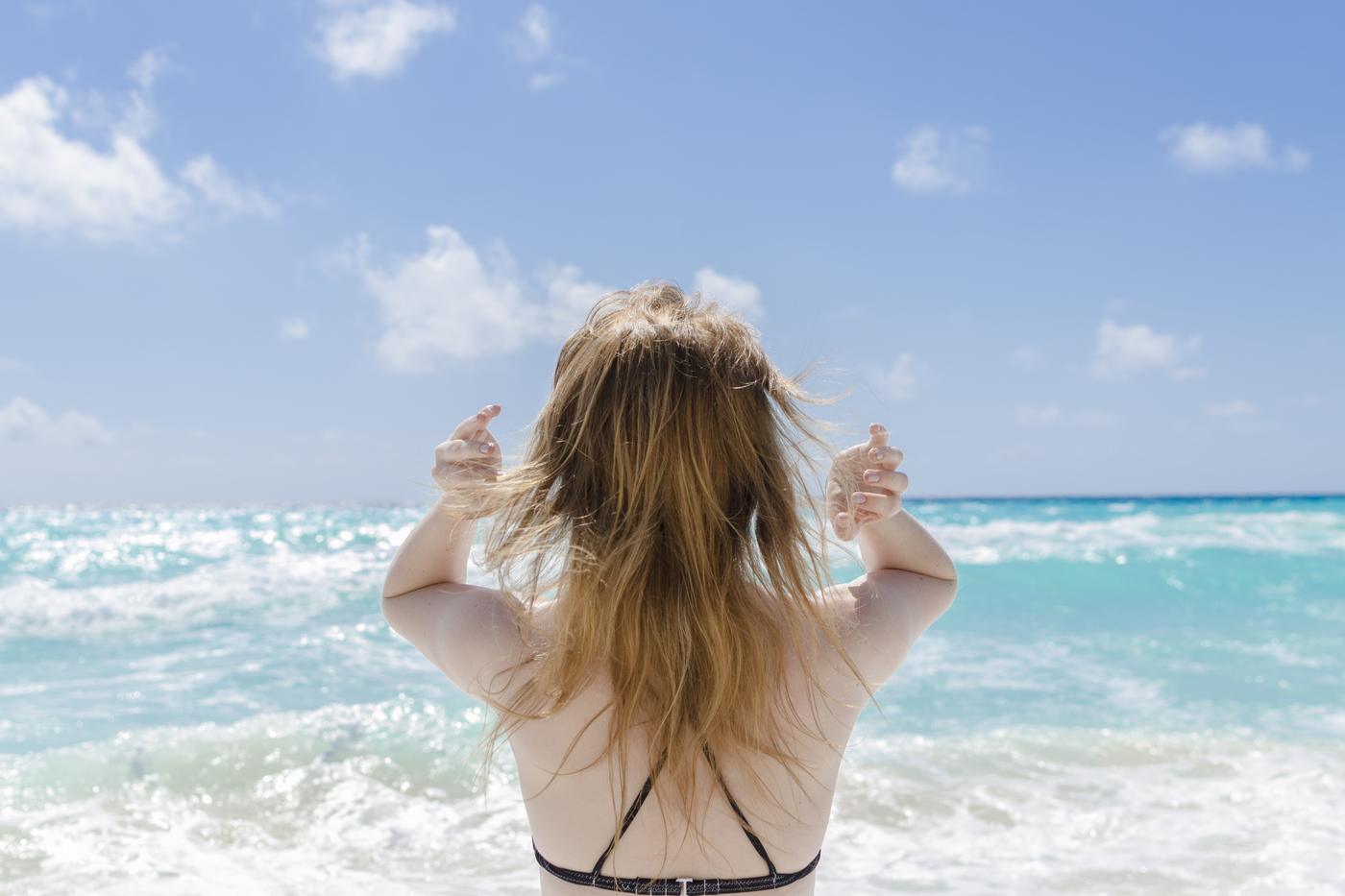 A traveler facing turquoise Caribbean surf on a beach in Cancun, Mexico